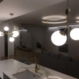 Nowoczesne oświetlenie wnętrza: kuliste lampy wiszące i okrągłe plafony LED w salonie z wyspą kuchenną i złotą armaturą.