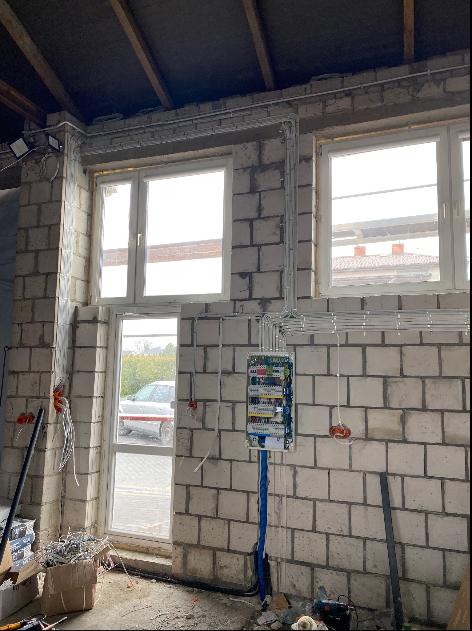 Rozdzielnica elektryczna z poprowadzonymi przewodami w nowym budynku z pustaków, widoczne puszki instalacyjne i niepodłączone przewody.