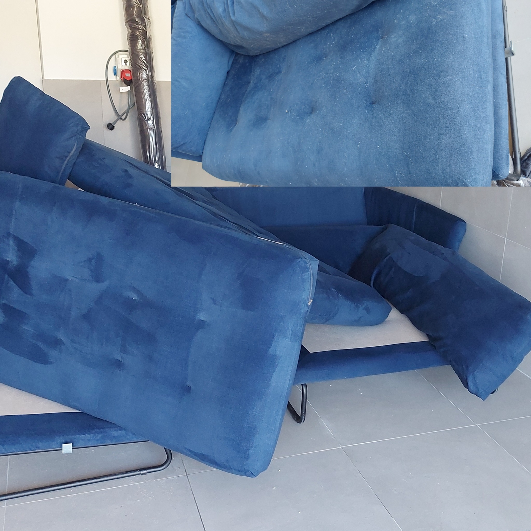 Rozłożona, niebieska sofa z welurową tapicerką, widoczne ślady użytkowania i niewielkie zabrudzenia przed czyszczeniem, w tle zwinięty dywan w folii.