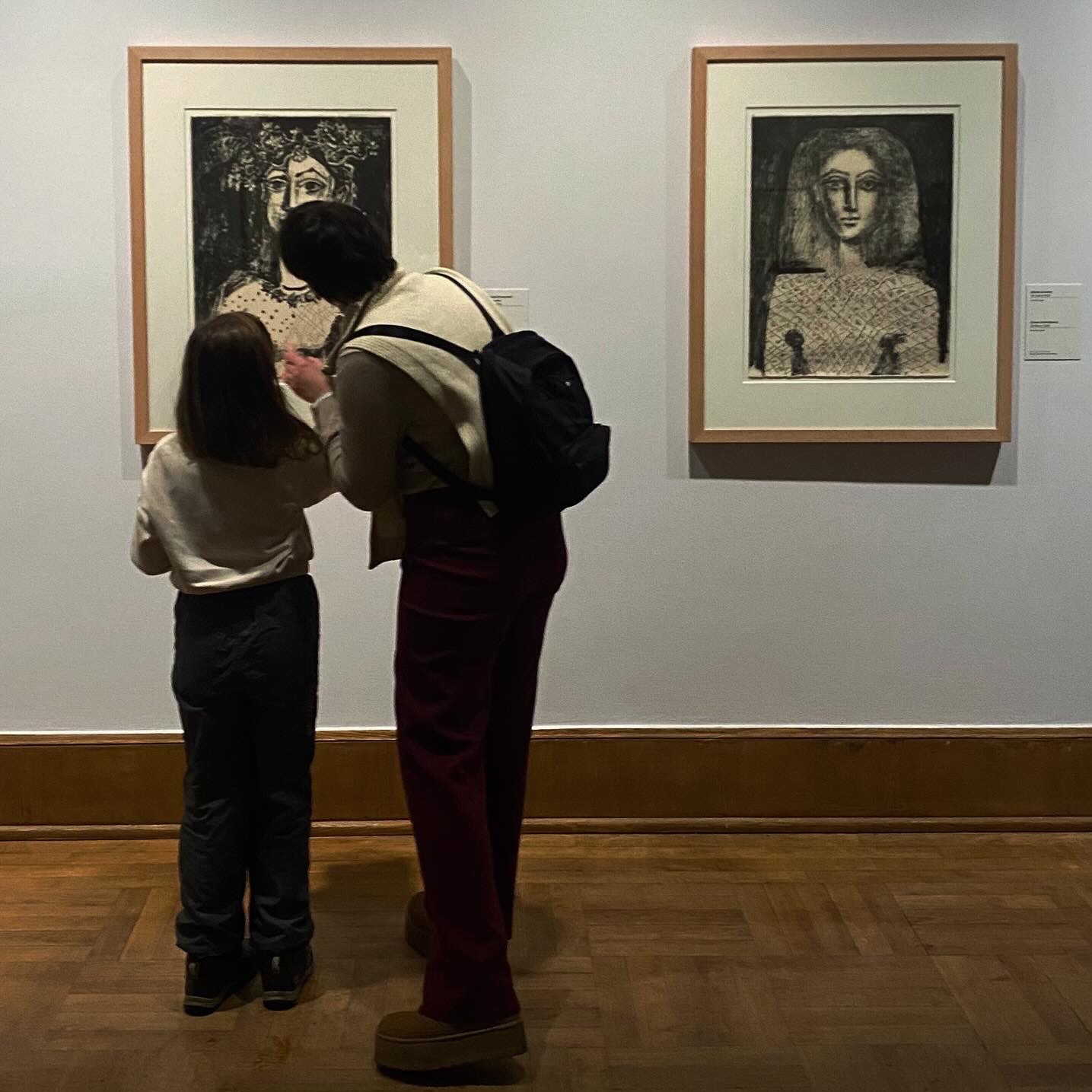 Wystawa w Warszawie: Dwie osoby, dorosła osoba z plecakiem i dziecko, oglądają czarno-białe portrety w drewnianych ramach wiszące na białej ścianie galerii. Dziecko wskazuje na jeden z portretów.