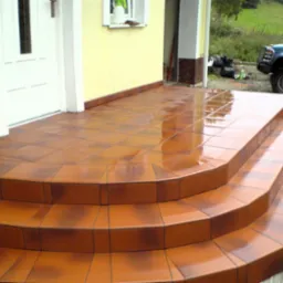 Błyszczący, brązowy taras z płytek ceramicznych z trzema schodkami prowadzącymi do drzwi wejściowych, widoczne odbicia na mokrej powierzchni, w tle zaparkowany samochód i worki ze śmieciami.