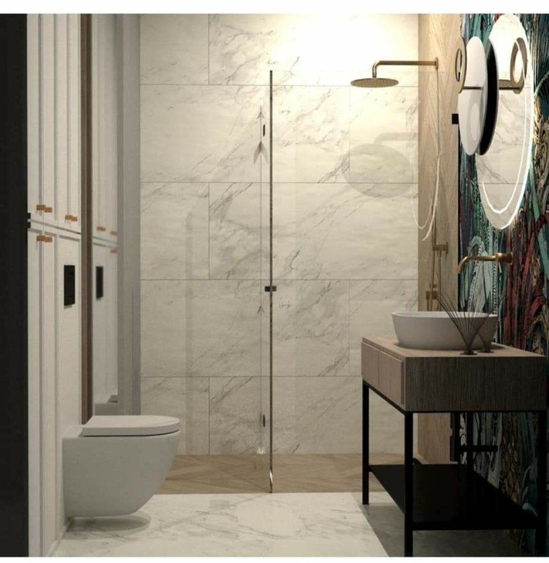 Nowoczesna łazienka z marmurowymi płytkami, kabiną prysznicową ze szklanymi drzwiami, wiszącą toaletą i umywalką na drewnianym blacie z czarnymi nogami oraz okrągłym lustrem z podświetleniem.