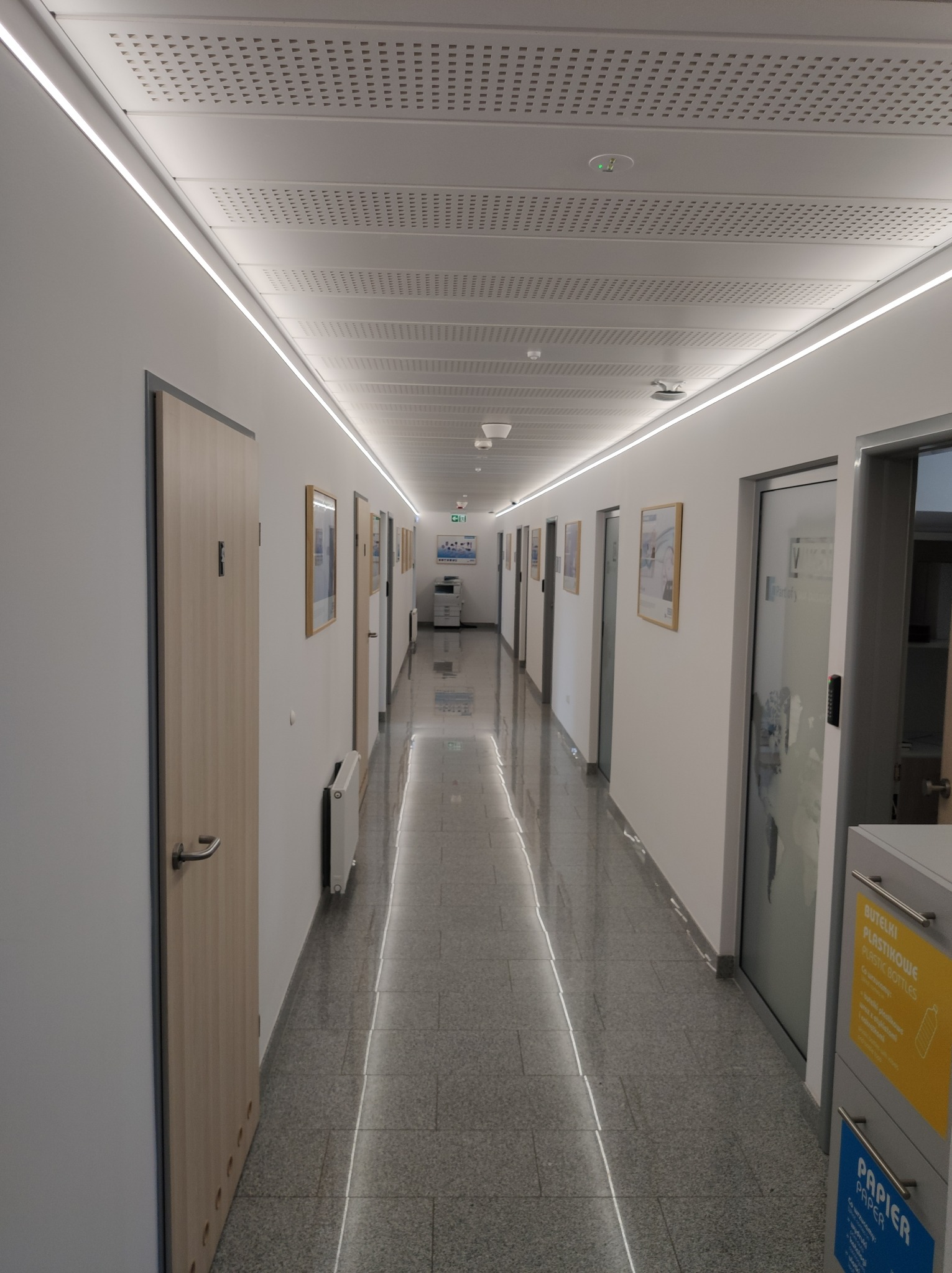 Korytarz biura oświetlony tylko paskami LED na ścianach.