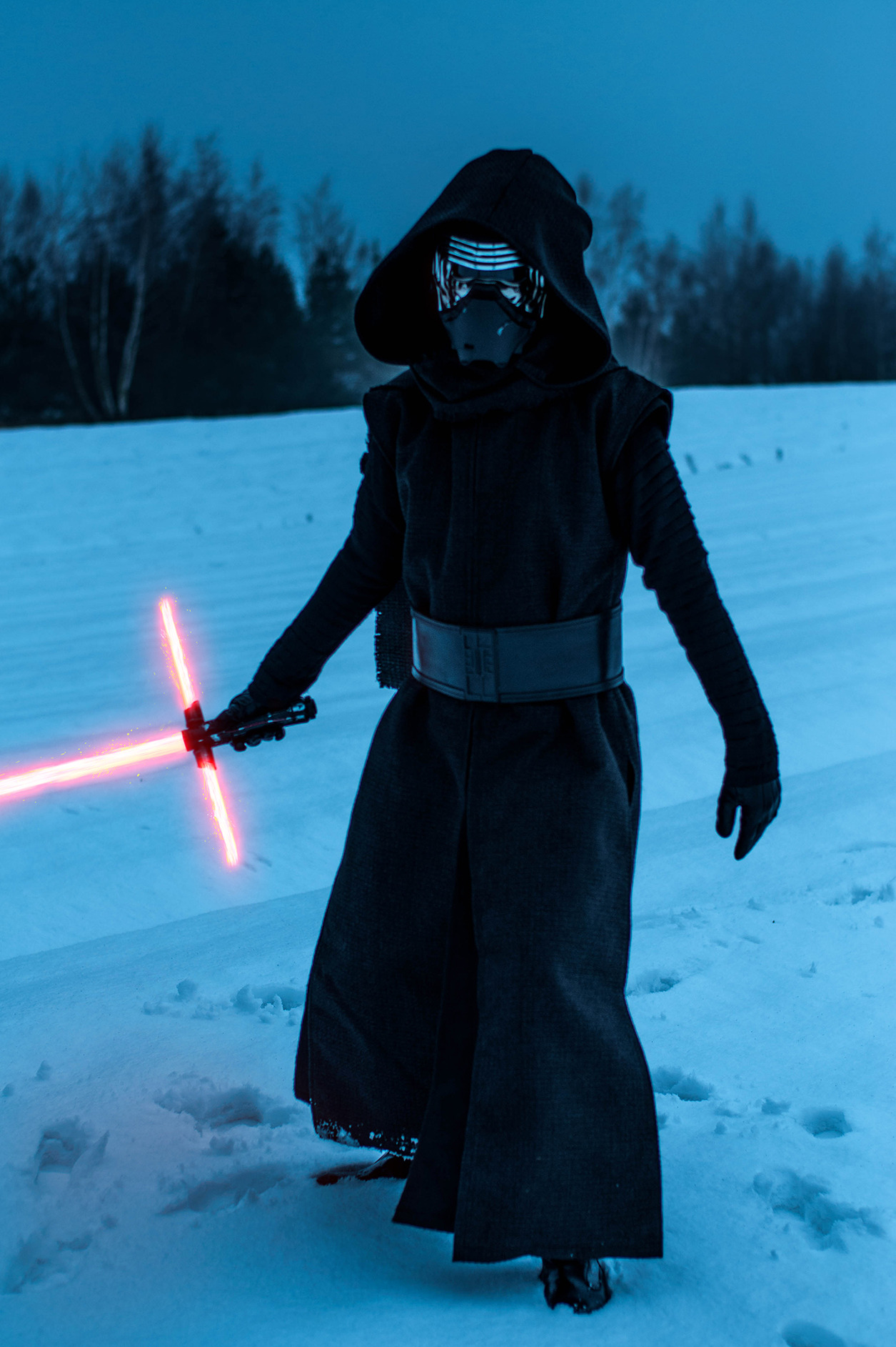 Osoba w kostiumie Kylo Rena z mieczem świetlnym na tle zimowego krajobrazu.