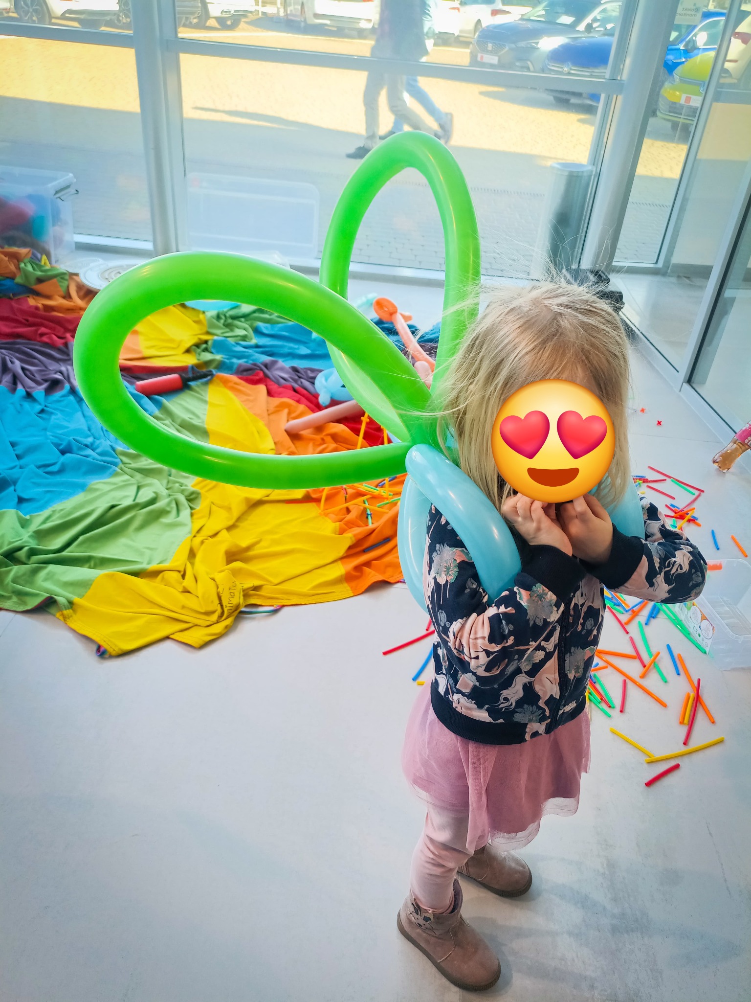 Dziewczynka z balonami w kształcie serca, kolorowe rekwizyty w tle. Atrakcje dla dzieci w Poznaniu, przygotowane przez animatora.