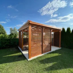 Pergola drewniana pokryta poliwęglanem komorowym, obudowana ruchomymi deseczkami.