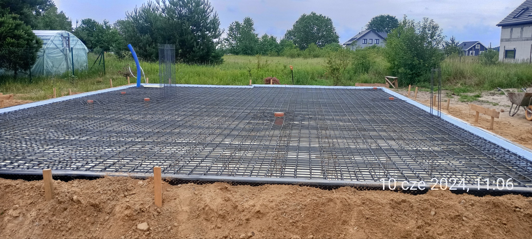 Zbrojenie płyty fundamentowej z widoczną izolacją obwodową oraz wystającymi elementami instalacji, przygotowane do zalania betonem.