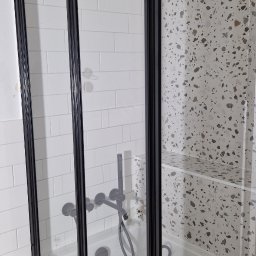 Mar-Greg - Szklana kabina prysznicowa z czarnymi profilami, białe płytki typu metro na ścianie i mozaika lastryko wewnątrz kabiny, bateria podtynkowa w kolorze czarnym.