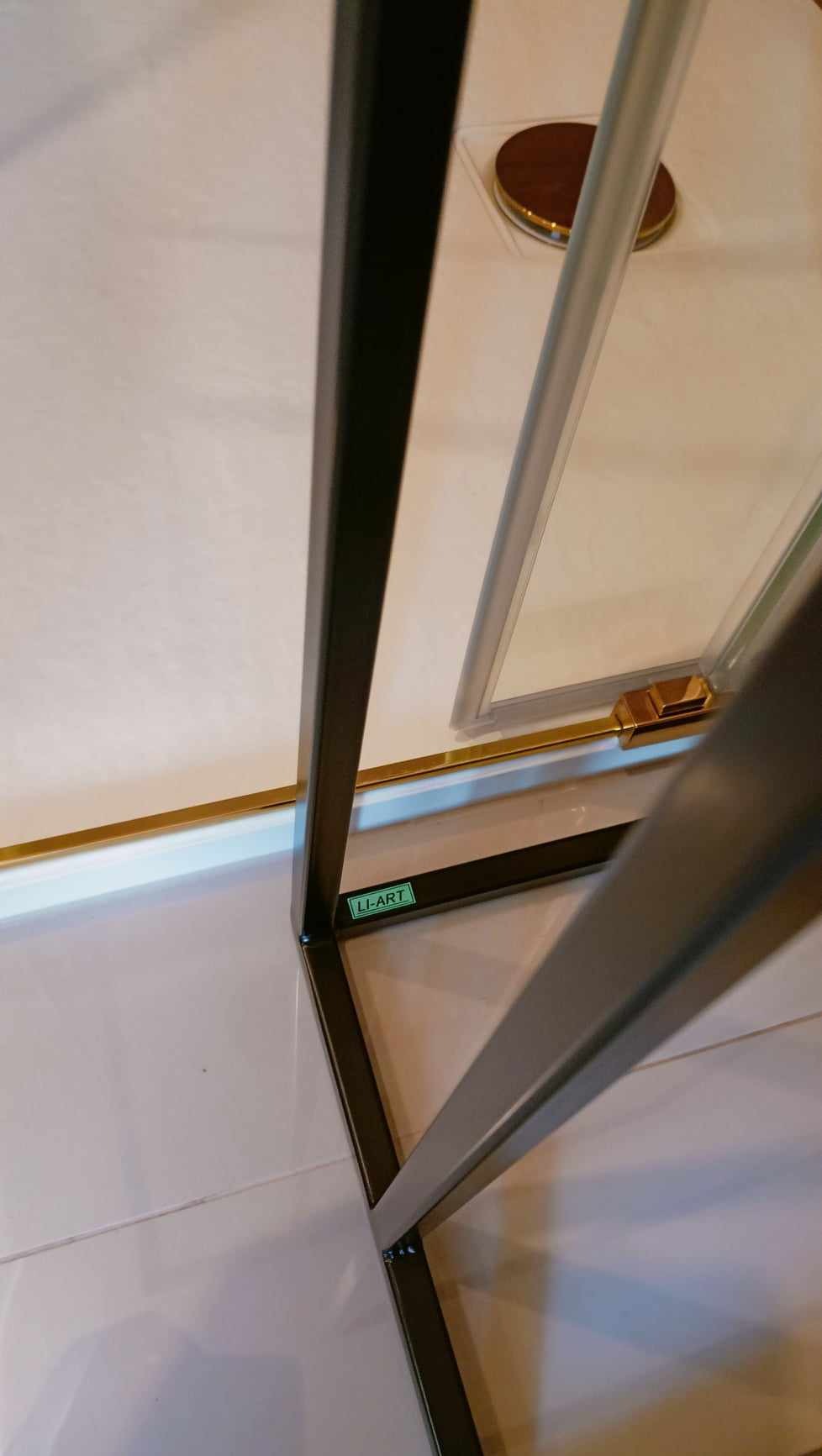 Metalowa konstrukcja z profilem kwadratowym, z widoczną etykietą 'LI-ART' oraz elementami szkła i złoconymi detalami, na jasnym tle.