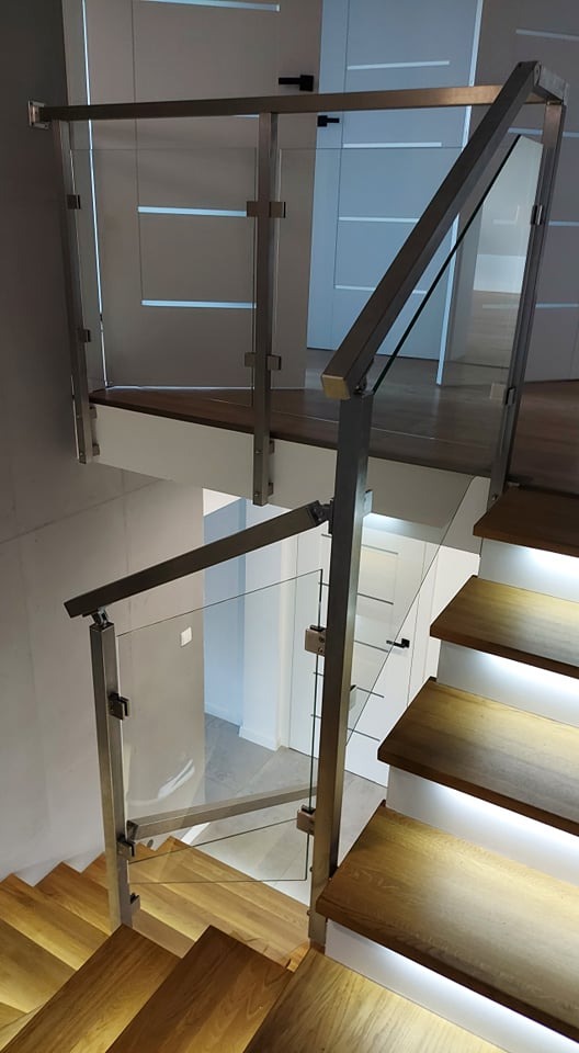 Schody drewniane z podświetleniem LED i balustradą ze stali nierdzewnej oraz szkła, widok z góry, nowoczesne wnętrze.