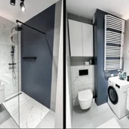 Nowoczesna łazienka z kabiną prysznicową typu walk-in, umywalką nablatową i pralką, wykończona płytkami w odcieniach szarości i bieli z akcentami czerni oraz niebieskiego, oświetlona punktowymi...