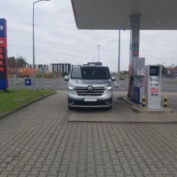 MTM Trans Mariusz Tyszecki - Srebrny van Renault Trafic na stacji paliw Moya, z widocznym cennikiem paliw i dystrybutorem.