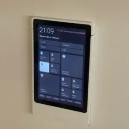 Panel sterowania inteligentnego domu zamontowany na ścianie, z widocznym interfejsem użytkownika i włączoną funkcją 'Sofa On'.