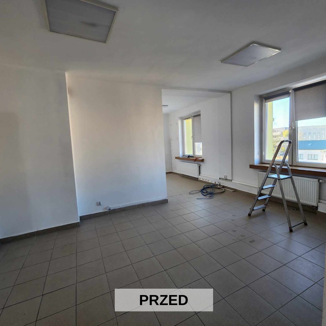 Puste biuro przed pracami remontowymi: białe ściany, brązowe płytki podłogowe, drabina oparta o grzejnik pod oknem, widoczne okablowanie na podłodze, napis 'PRZED' na dole zdjęcia.