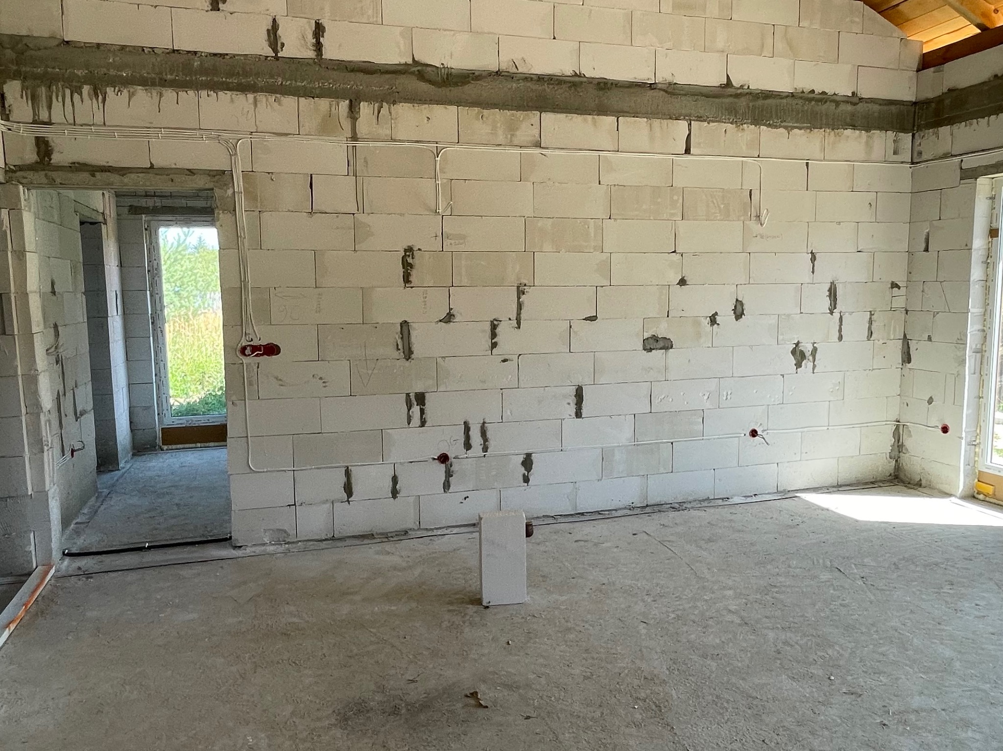 Wnętrze w trakcie prac elektrycznych: widoczne przewody i puszki instalacyjne na ścianach z betonu komórkowego. Surowy stan, przygotowanie do dalszych prac wykończeniowych.