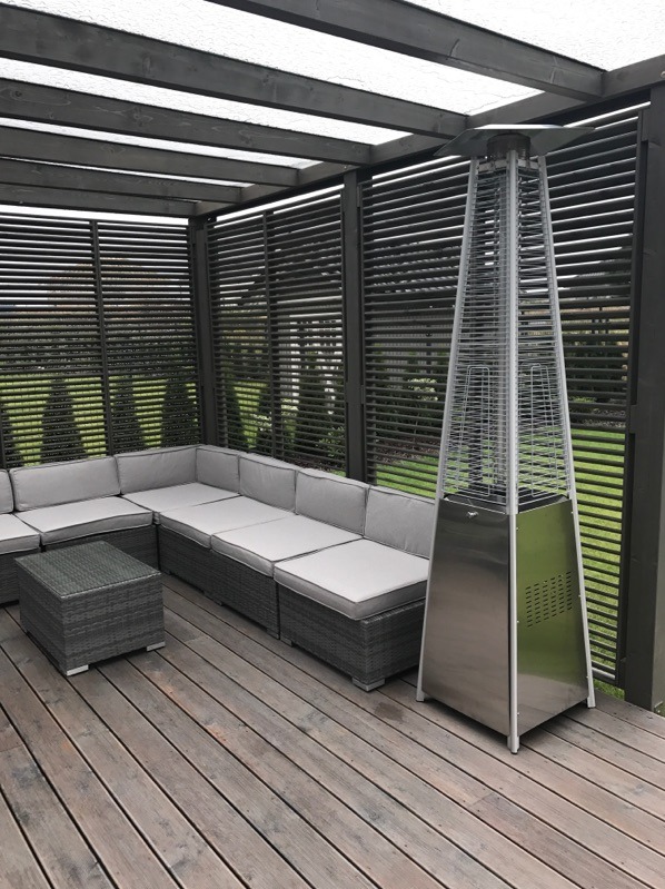 Zadaszony taras z meblami ogrodowymi i grzejnikiem piramidą. Drewniana konstrukcja z żaluzjowymi ścianami. Nowoczesny design.