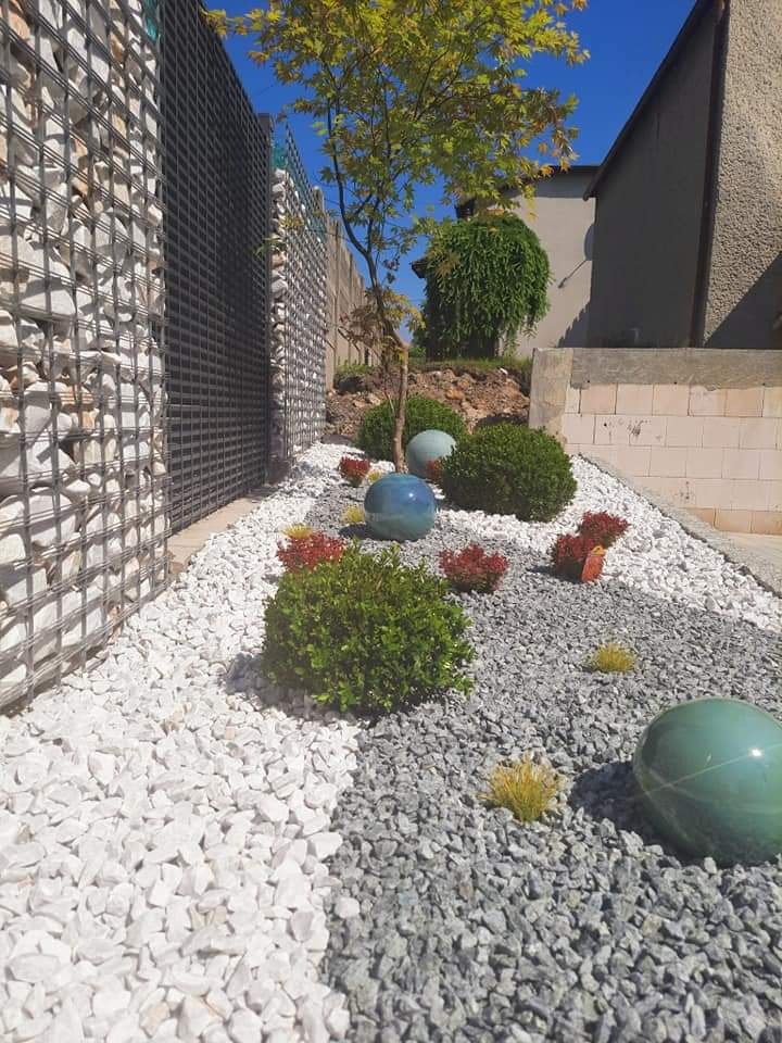 Ogród z podziałem na strefy: białe i szare kamienie, kuliste krzewy, drzewo japońskie, gabion z kamienia i dekoracyjne, ceramiczne kule w kolorze turkusowym.