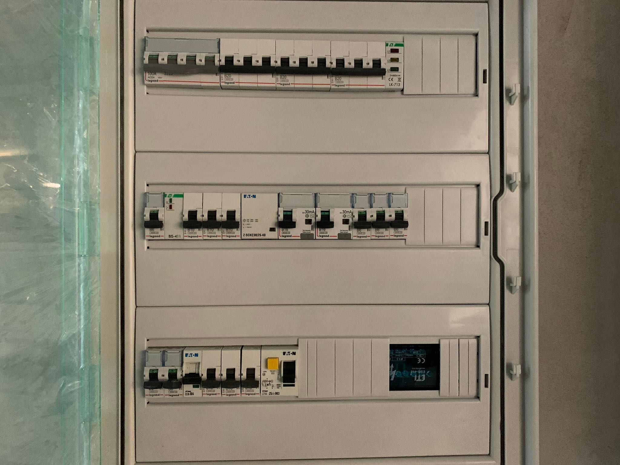 Rozdzielnica elektryczna z bezpiecznikami Legrand i EATON, widok z bliska na zamontowane zabezpieczenia w skrzynce elektrycznej w kolorze białym.