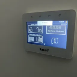 Panel sterowania systemem alarmowym Satel z ekranem dotykowym, wyświetlający status alarmu jako nieaktywny, z ikonami bramy garażowej i wjazdowej, zamka otwartego i zamkniętego.