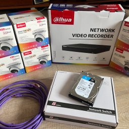 SWS Instal - Zestaw do monitoringu Dahua: kamery, rejestrator, dysk twardy Seagate SkyHawk i switch sieciowy GetFort, ułożone na podłodze.