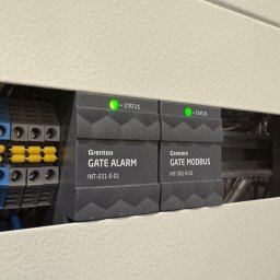 SWS Instal - Panel sterowania Grenton Smart Home z modułami Gate Alarm i Gate Modbus, diody statusu świecą na zielono, widoczne złącza elektryczne.