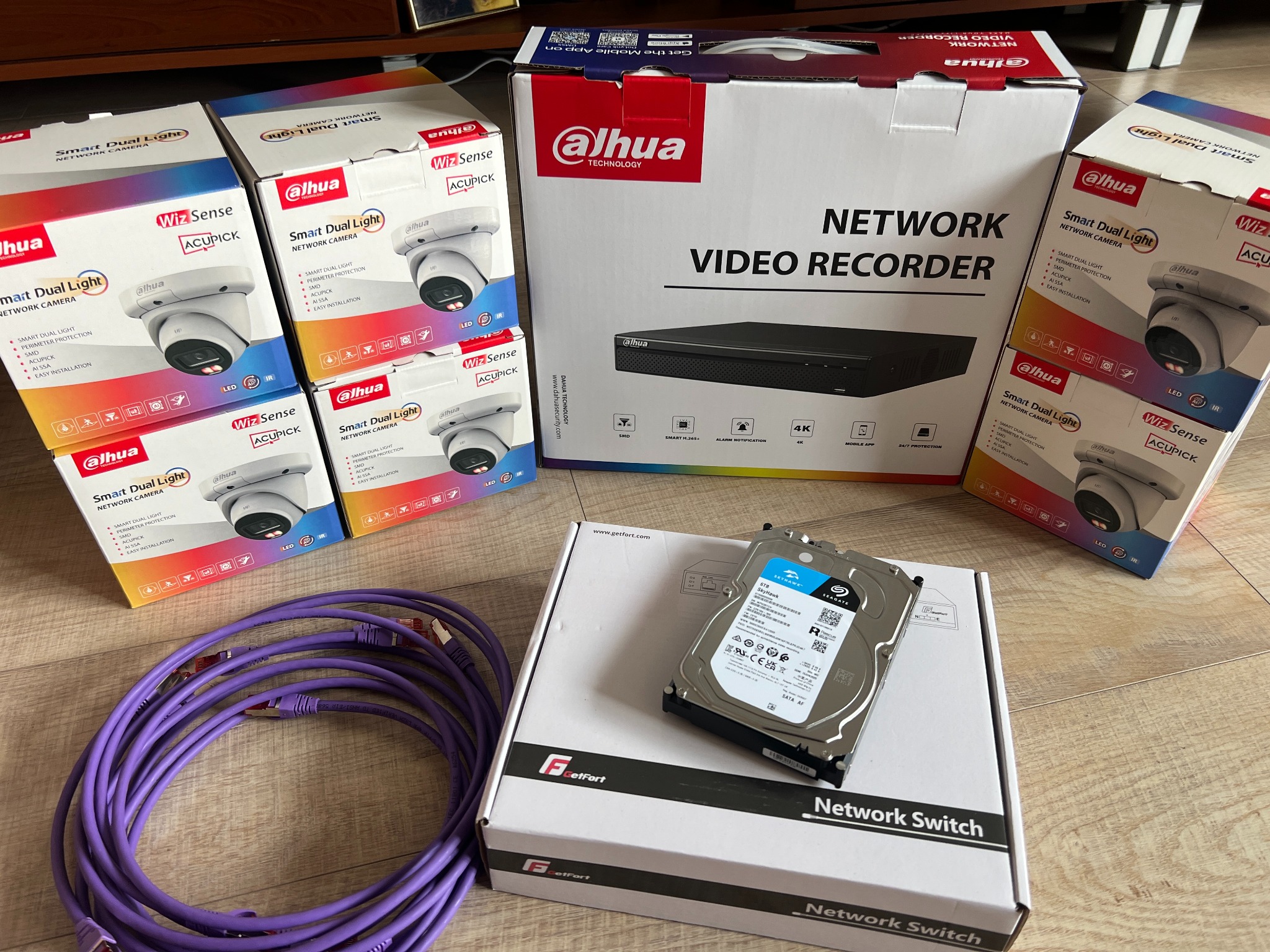 Zestaw do monitoringu Dahua: kamery, rejestrator, dysk twardy Seagate SkyHawk i switch sieciowy GetFort, ułożone na podłodze.