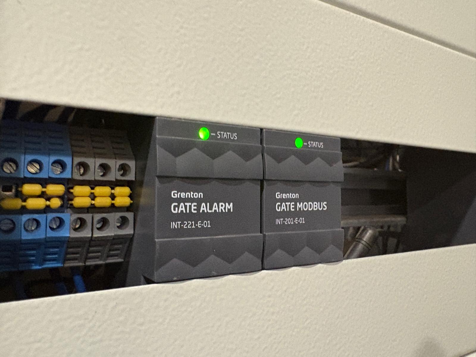 Panel sterowania Grenton Smart Home z modułami Gate Alarm i Gate Modbus, diody statusu świecą na zielono, widoczne złącza elektryczne.
