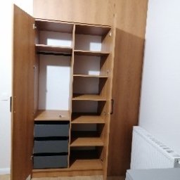 Studio mebli FABIANI - Jasna, drewniana szafa na wymiar z otwartymi drzwiami, ukazująca półki, drążek i szuflady. Widoczne detale wykończenia i funkcjonalne wnętrze.