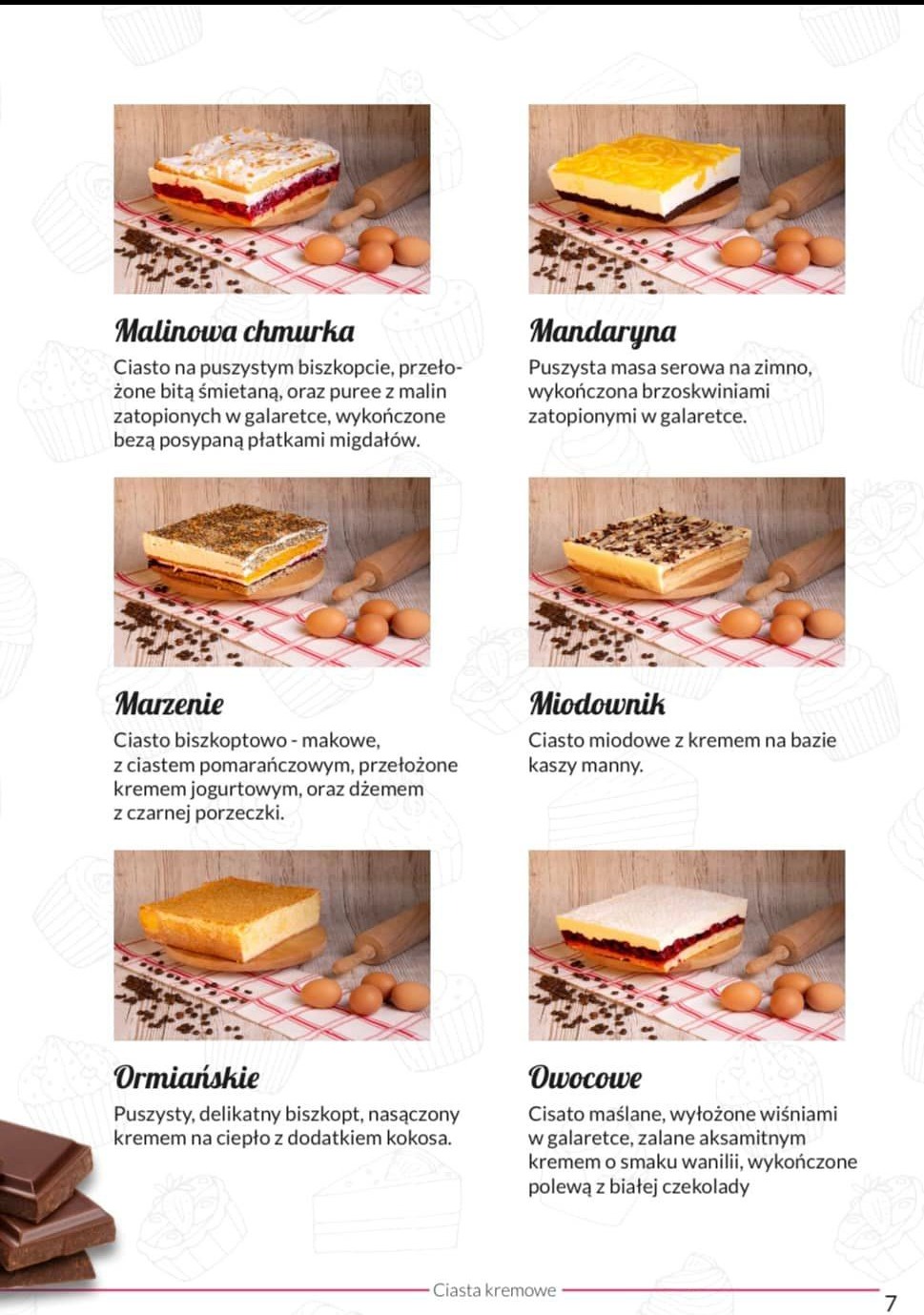 Zestawienie sześciu ciast kremowych o różnych smakach, udekorowanych owocami i galaretką, prezentowanych na drewnianych deskach z jajkami i wałkiem w tle.