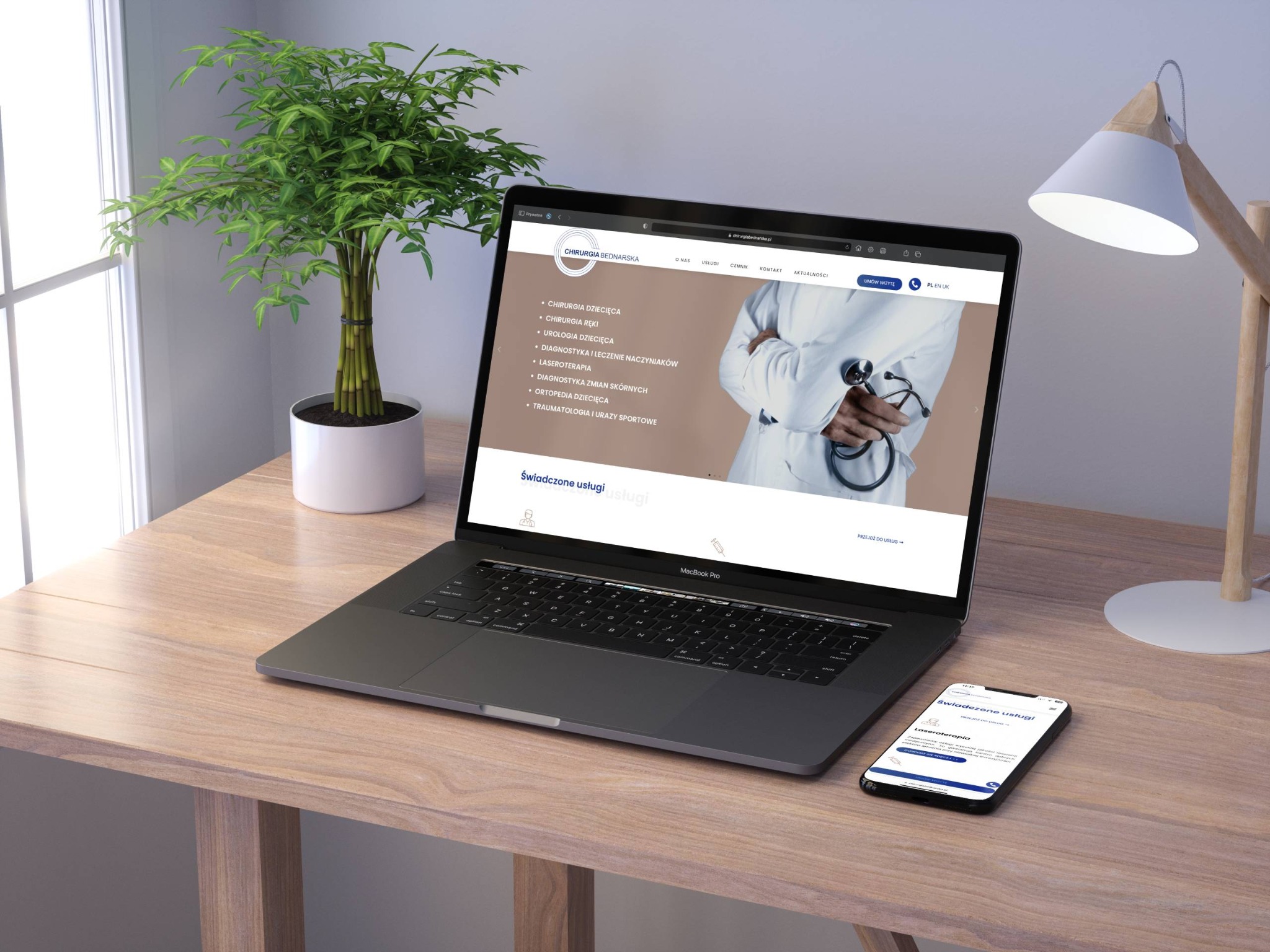 Laptop MacBook Pro i smartfon na drewnianym biurku prezentują stronę internetową kliniki medycznej z ofertą chirurgii dziecięcej, laseroterapii i innych specjalizacji. Obok stoi roślina w białej...