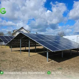 Instalacja fotowoltaiczna naziemna o mocy 24 kWp w Siemiątkowie, woj. Mazowieckie, z panelami na metalowych podporach, widoczny budynek mieszkalny w tle i samochód dostawczy firmy instalacyjnej.