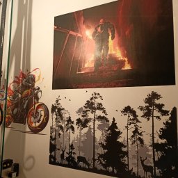 M.B.PROJECT - Na ścianie wiszą trzy plakaty: strażak na tle ognia, motocyklista z płomieniami i sylwetki drzew i jeleni.