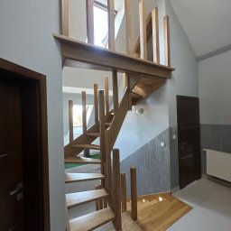 Ufarbiorza - Drewniane schody z jasnego drewna, z pionowymi słupkami zamiast balustrady, prowadzące na antresolę z oknem dachowym. Minimalistyczny design, nowoczesne wykończenie wnętrza.