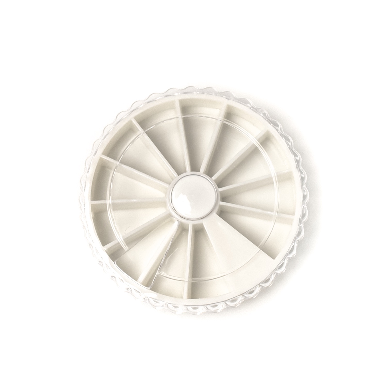 Puste, okrągłe pudełko z przegródkami w kształcie wycinków koła, wykonane z białego tworzywa sztucznego z przezroczystym, karbowanym brzegiem.