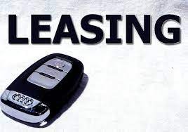 Kluczyk samochodowy Audi z napisem LEASING w górnej części zdjęcia, na jasnym, rozmytym tle.