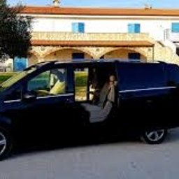 OTO TAXI & BUS ZAKOAPNE - Czarny, lśniący Mercedes-Benz Vito z otwartymi drzwiami przesuwnymi, zaparkowany na żwirowym podjeździe przed dwupiętrowym budynkiem z białymi ścianami i niebieskimi okiennicami, otoczony zielenią.