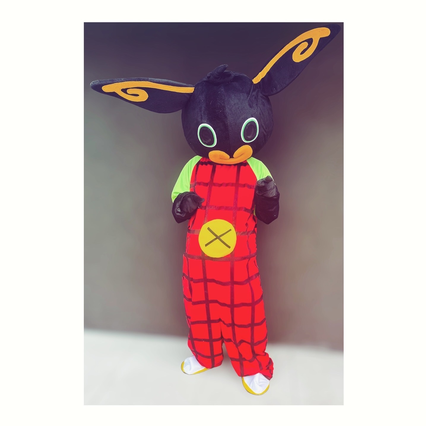 Osoba w kostiumie Binga, popularnej postaci z bajki dla dzieci, stojąca na tle szarej ściany.