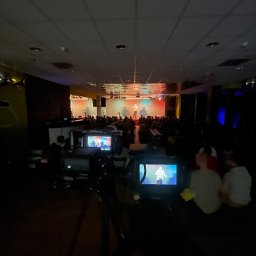 KO.REC MEDIA SPÓŁKA Z OGRANICZONĄ ODPOWIEDZIALNOŚCIĄ - Kamera ustawiona na statywie rejestruje występ na scenie przed publicznością; widoczny ekran kamery z podglądem obrazu.
