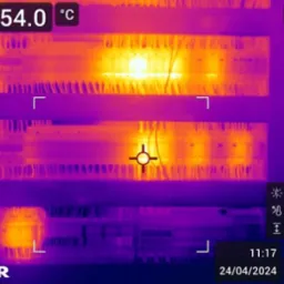 Termogram rozdzielnicy elektrycznej z widocznymi punktami o podwyższonej temperaturze, zarejestrowany urządzeniem FLIR.