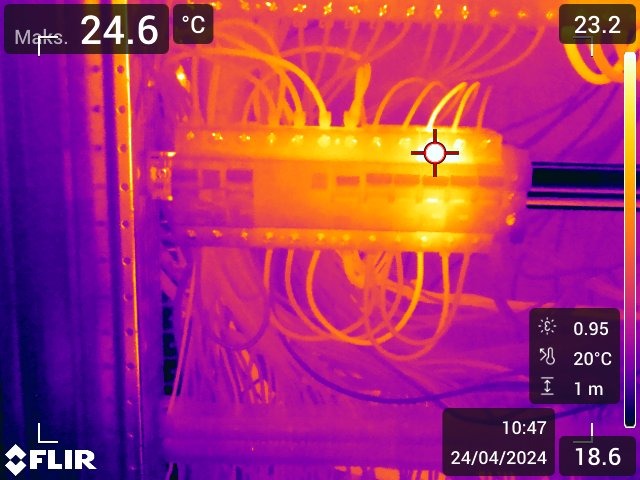 Obraz termowizyjny rozdzielnicy elektrycznej z widocznymi przewodami, wskazujący na temperaturę poszczególnych elementów.