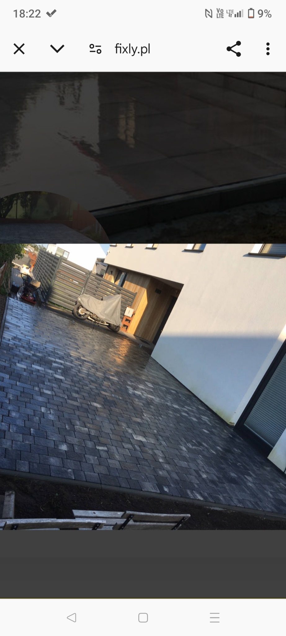 Ułożona kostka brukowa w kolorze grafitowym przed nowoczesnym domem z elementami drewnianymi, motocykl pod pokrowcem w tle, widoczna myjka ciśnieniowa.