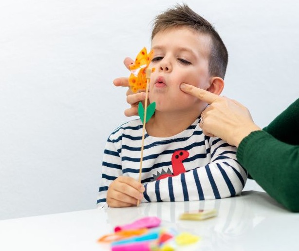 Chłopiec z dinozaurem na koszulce ćwiczy wymowę z pomocą terapeuty i pacynki w Trzebnicy.