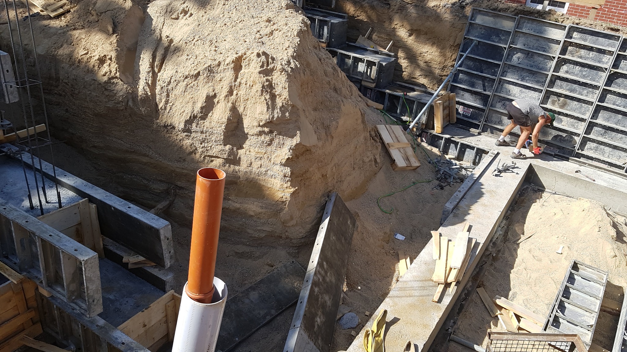 Prace ziemne i betonowanie fundamentów w Zgorzelcu: widok na wykop z szalunkami, zbrojeniami i pracownikiem w trakcie robót.