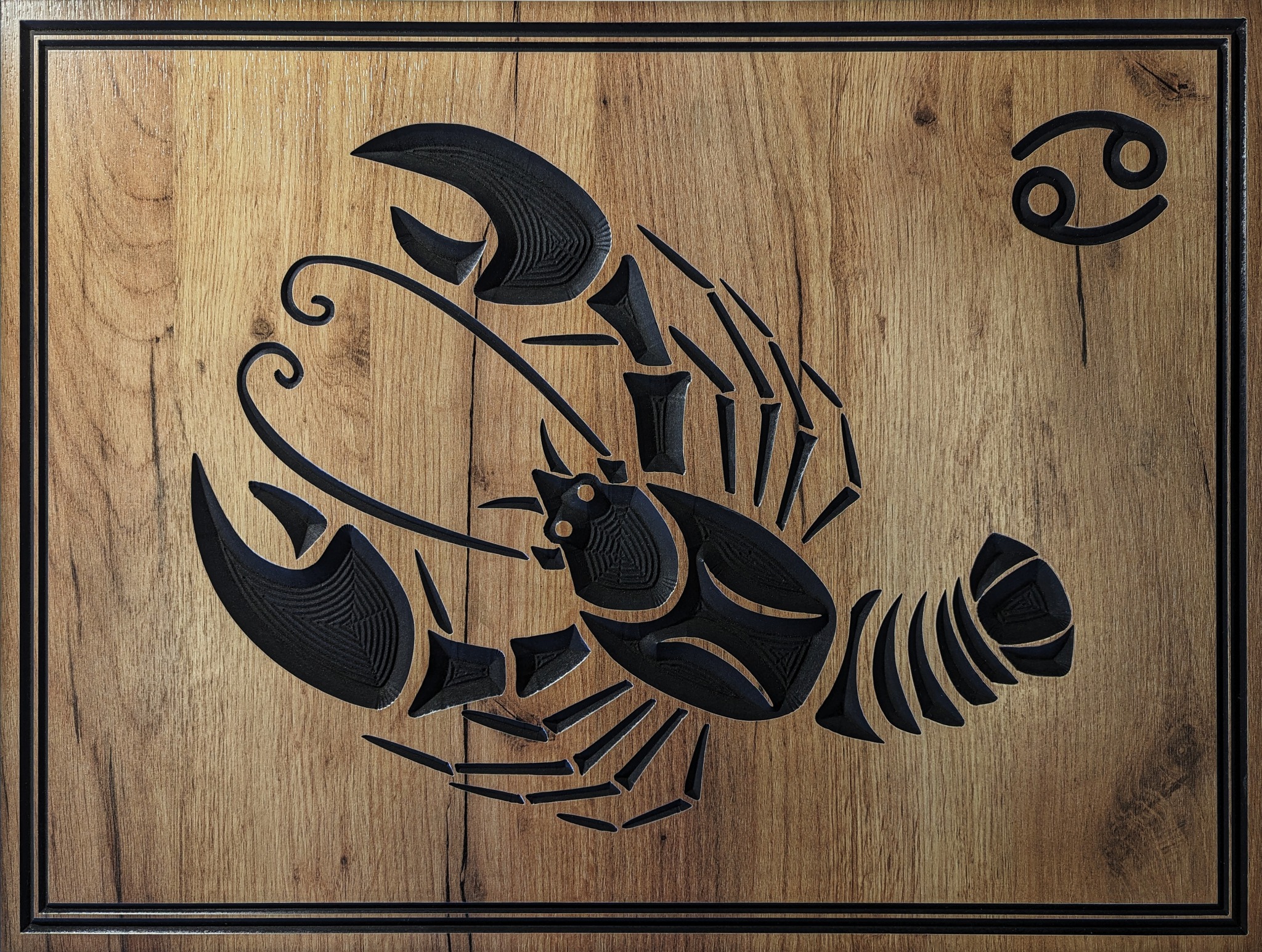 Drewniana płaskorzeźba przedstawiająca znak zodiaku Rak, z czarnym symbolem raka i znakiem zodiaku na tle desek z wyraźnym usłojeniem, otoczona czarną ramą.