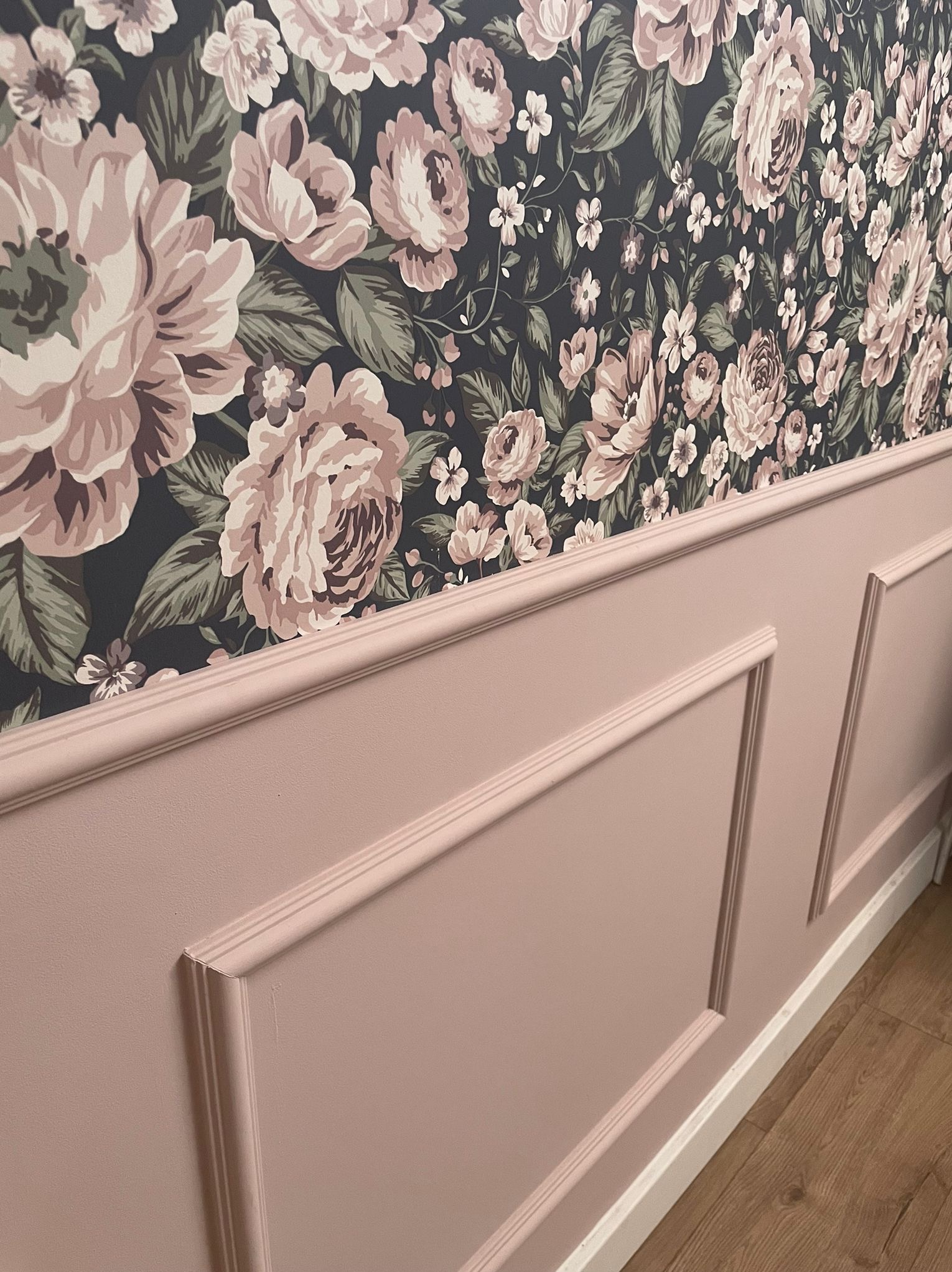 Ściana z dekoracyjnym, różowym panelem i tapetą w kwiaty, widok z boku.