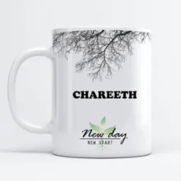 Biały kubek z nadrukowanym imieniem 'CHAREETH' pod gałęziami drzewa i napisem 'New day New start' z motywem roślinnym, prezentowany na jasnym tle.