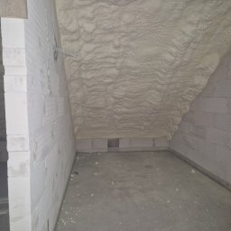 Z.U.A EKTOR - Poddasze z izolacją pianką PUR, widoczne ściany z bloczków betonowych i przewody elektryczne.