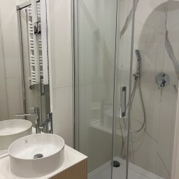 CUADRO PLUS Mariia Alfimova - Nowoczesna łazienka z okrągłą umywalką nablatową marki Laufen, kabiną prysznicową ze szklanymi drzwiami i grzejnikiem drabinkowym w jasnej kolorystyce.