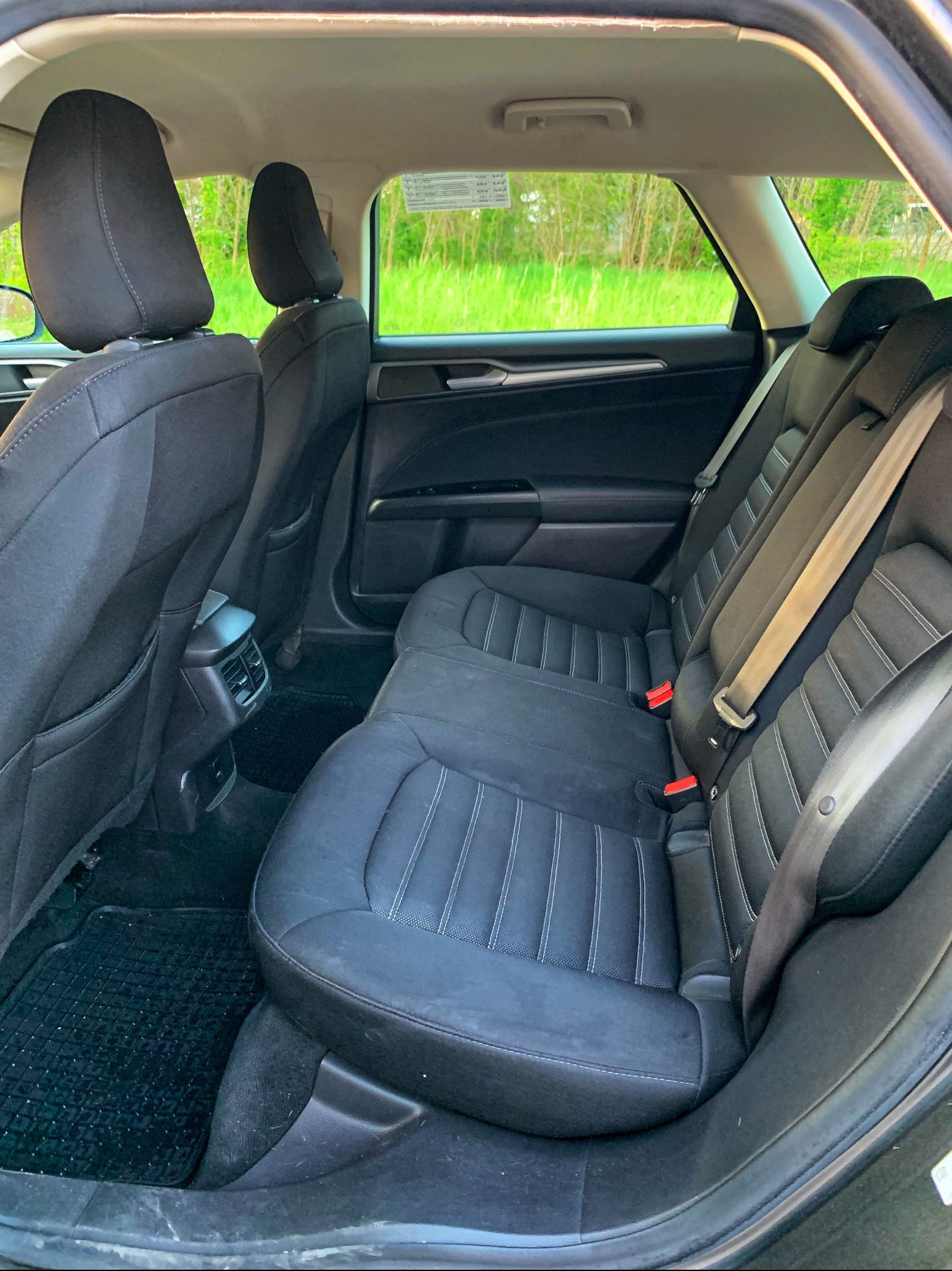 Wnętrze samochodu osobowego z czarną tapicerką i widokiem na zieloną łąkę za oknem, Łódź.