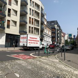 Easy Movers - Ciężarówka z reklamą usług transportowych zaparkowana na ulicy w mieście, z widocznymi budynkami mieszkalnymi w tle.